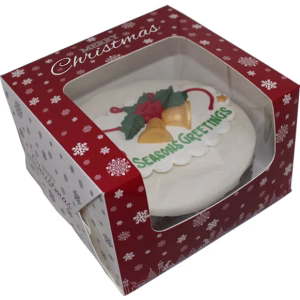 Top-down view through clear window panel of red Christmas box displaying decorated round cake with holly decoration